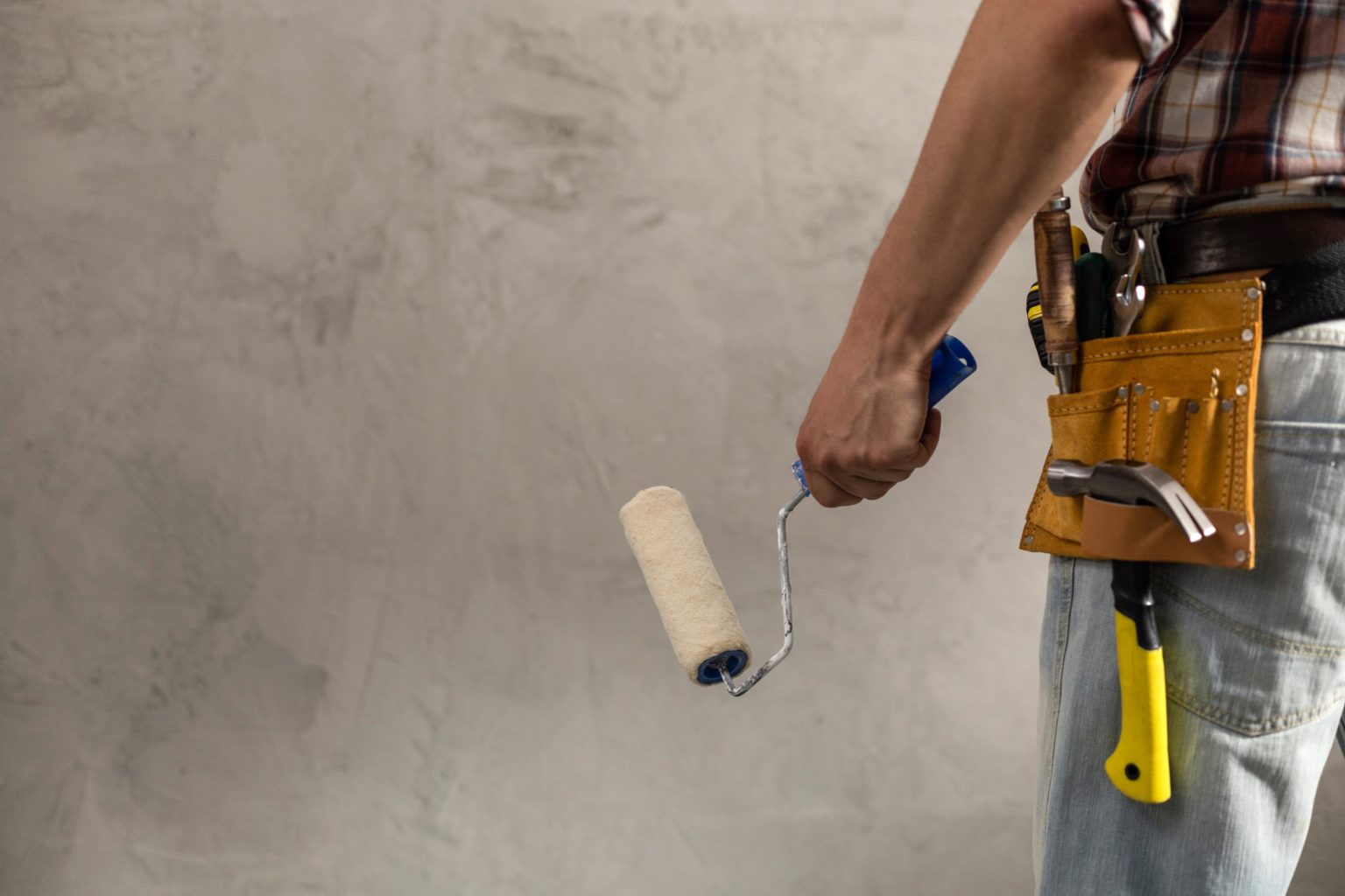 Trabajador aplicando pintura con rodillo en obra de construcción