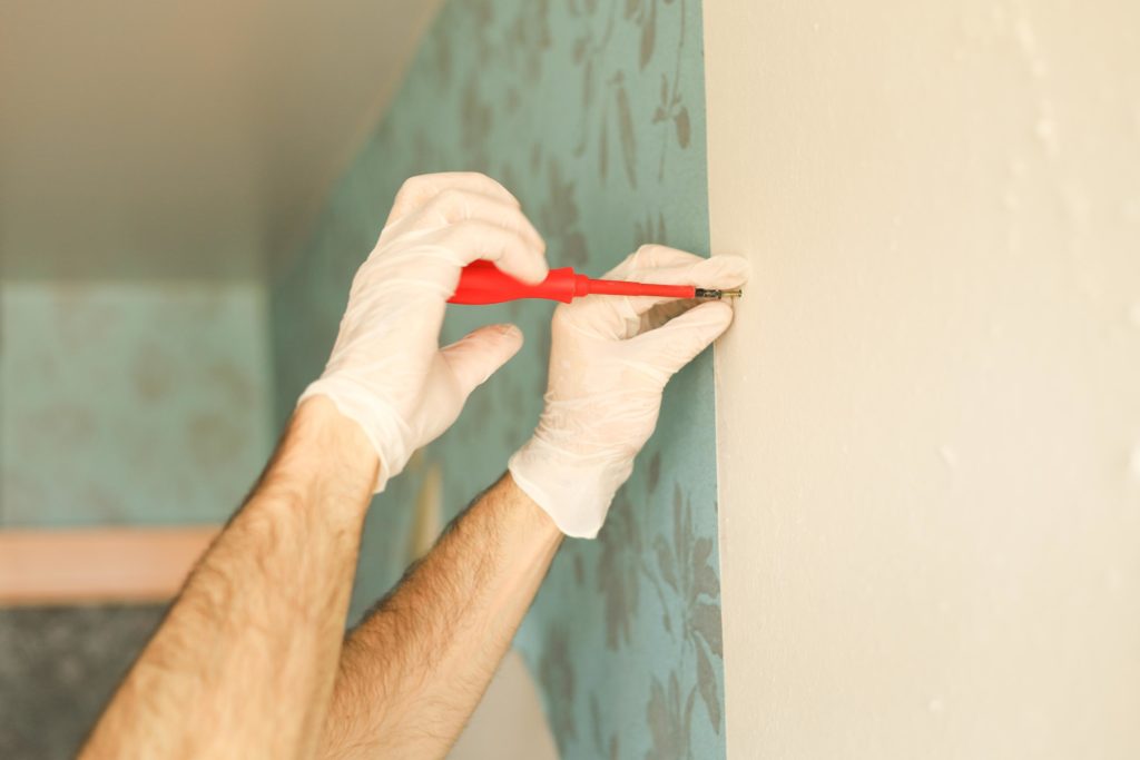 manos masculinas atornillando pared