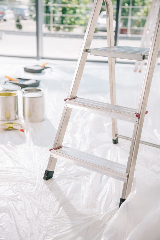 Enfoque selectivo de una escalera en habitación con botes de pintura